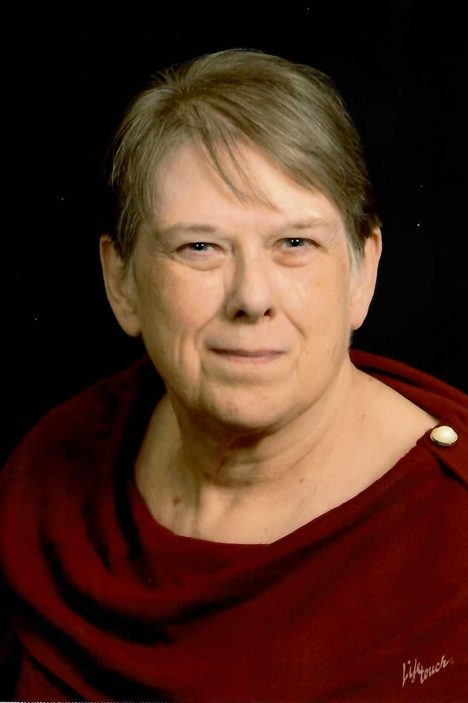 A woman wearing glasses and a white shirt is smiling for the camera.