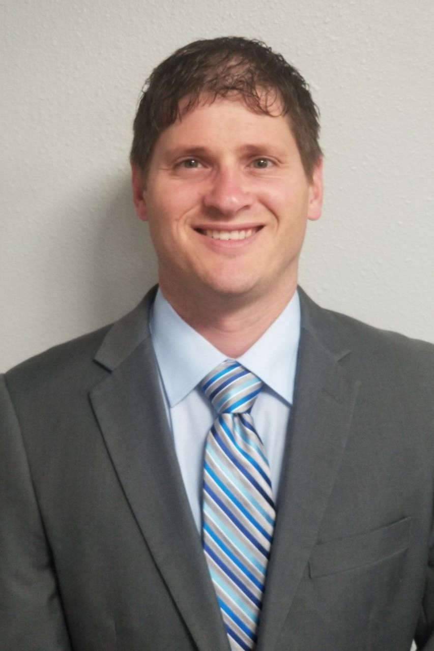 A woman wearing glasses and a white shirt is smiling for the camera.