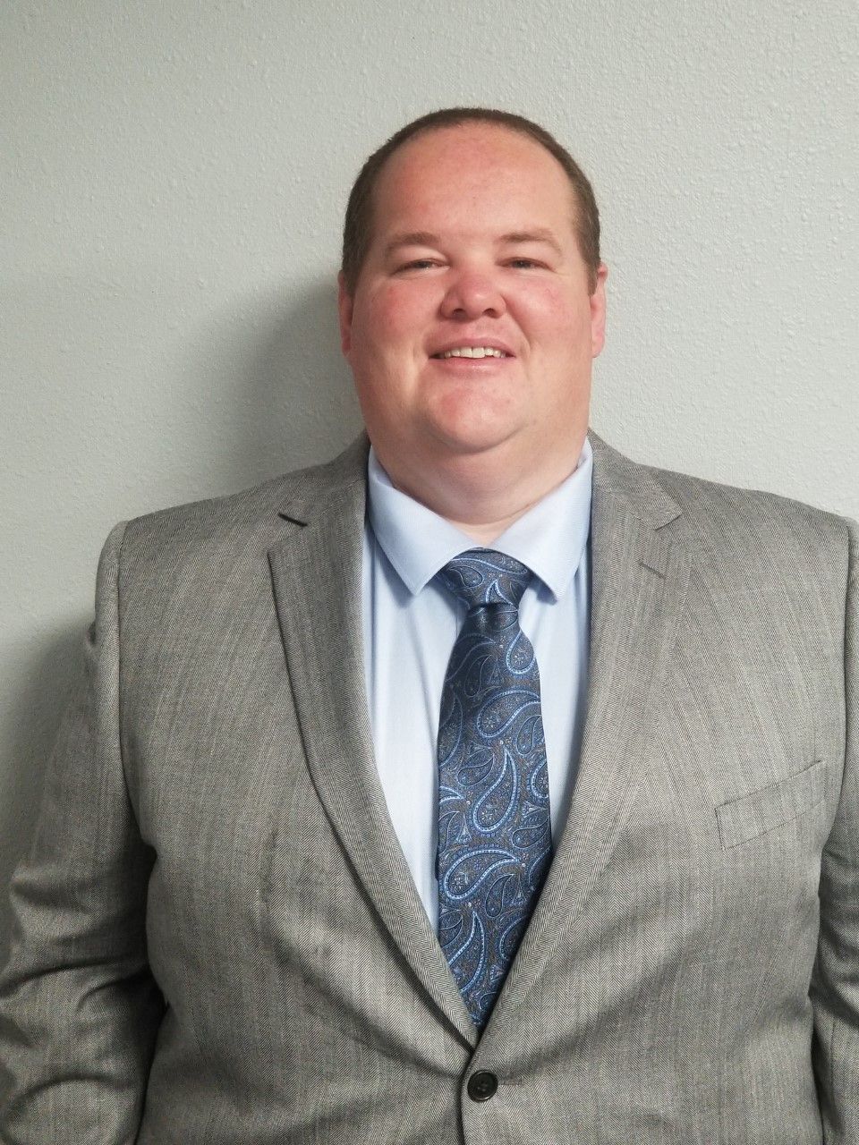 A woman wearing glasses and a white shirt is smiling for the camera.