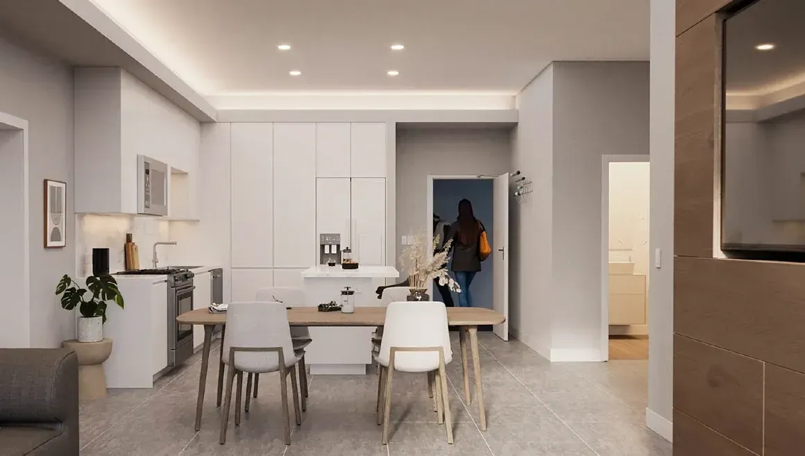 A dining room with a table and chairs and a kitchen in the background.