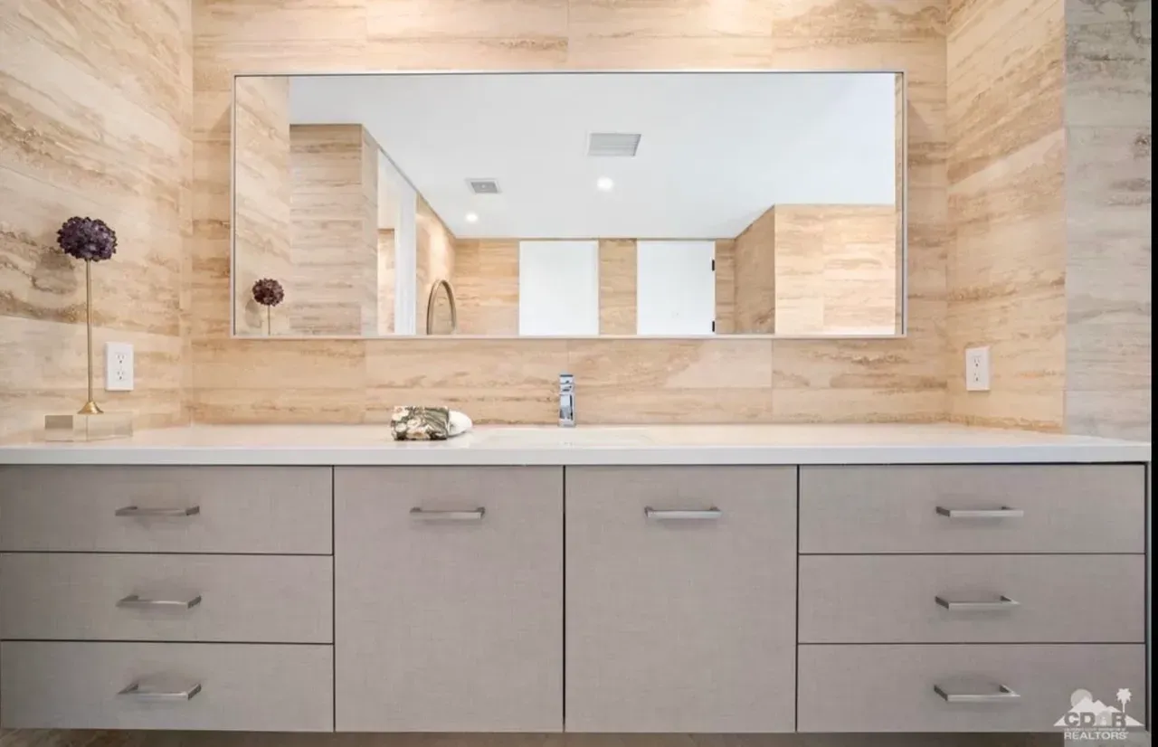 A bathroom with a large mirror and a sink.