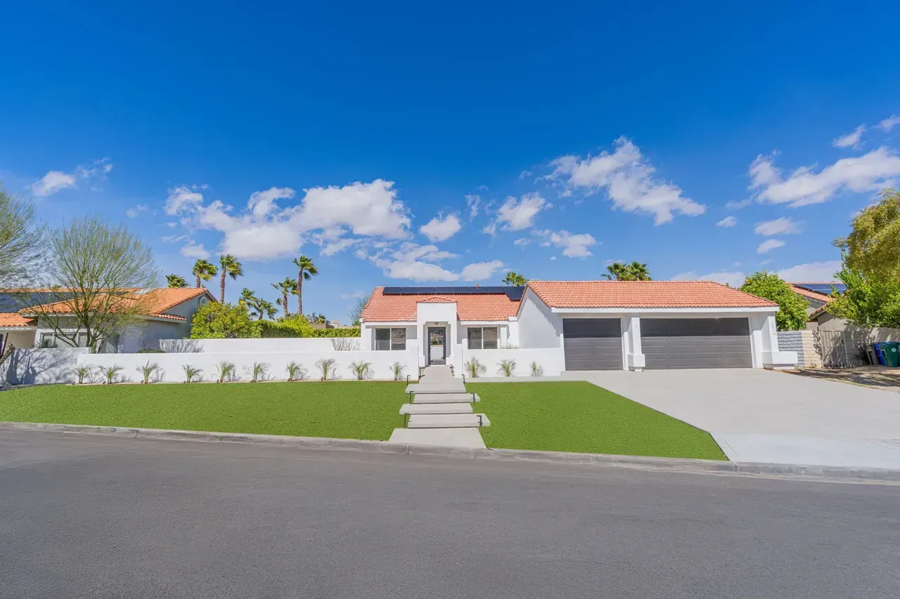 A large white house with a red tile roof is for sale.