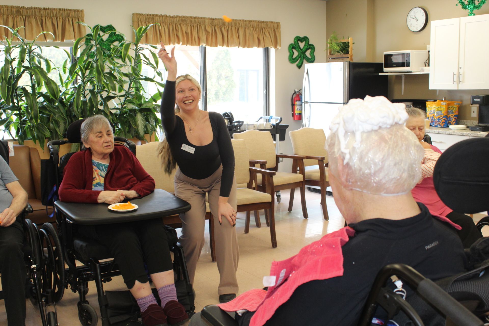 Residents and staff gathered in a bright common room during a social activity