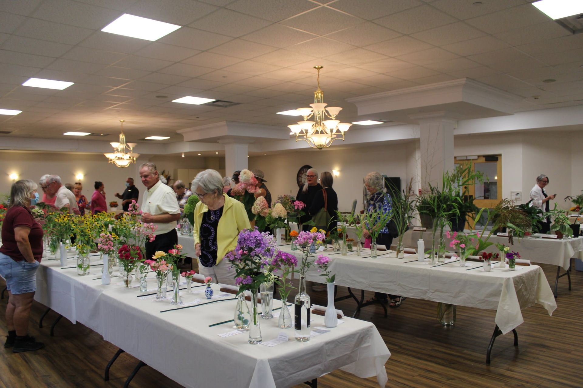 Banquet hall with guests standing around decorated tables and floral centerpieces