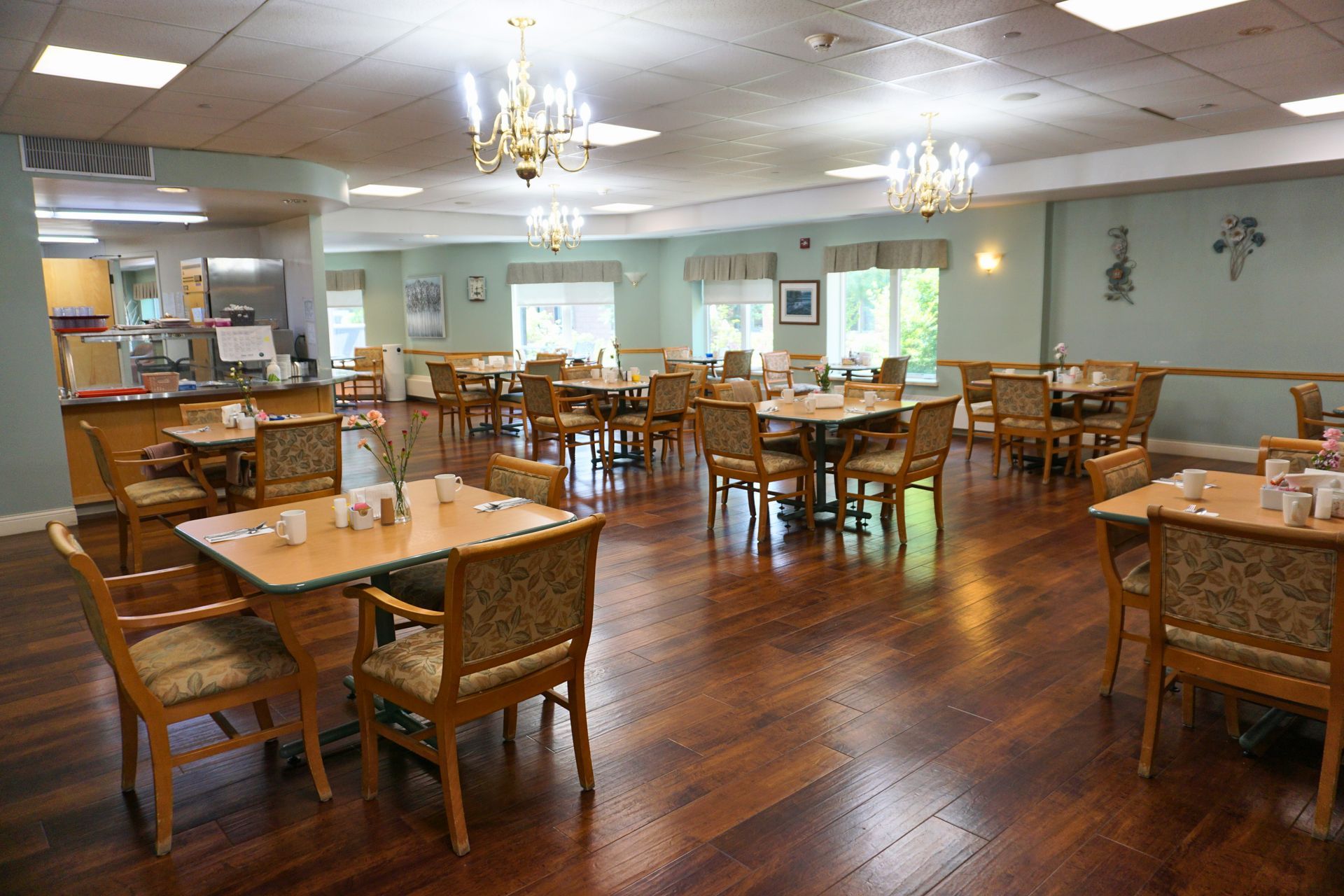 Spacious dining room with wooden tables and chairs, polished floors, and bright windows.
