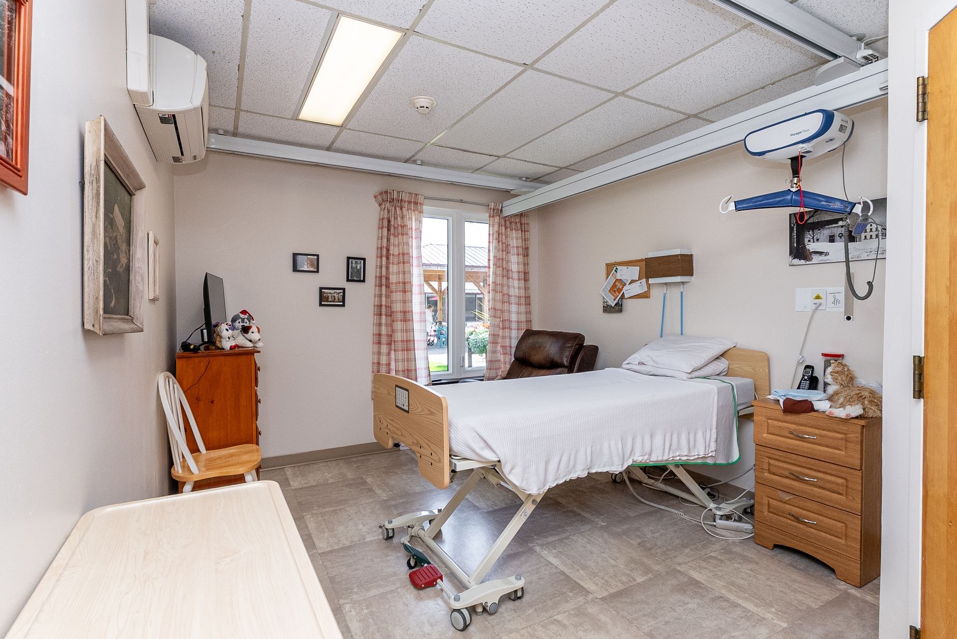 Hospital room with an empty bed, medical equipment, and a cabinet by a window.