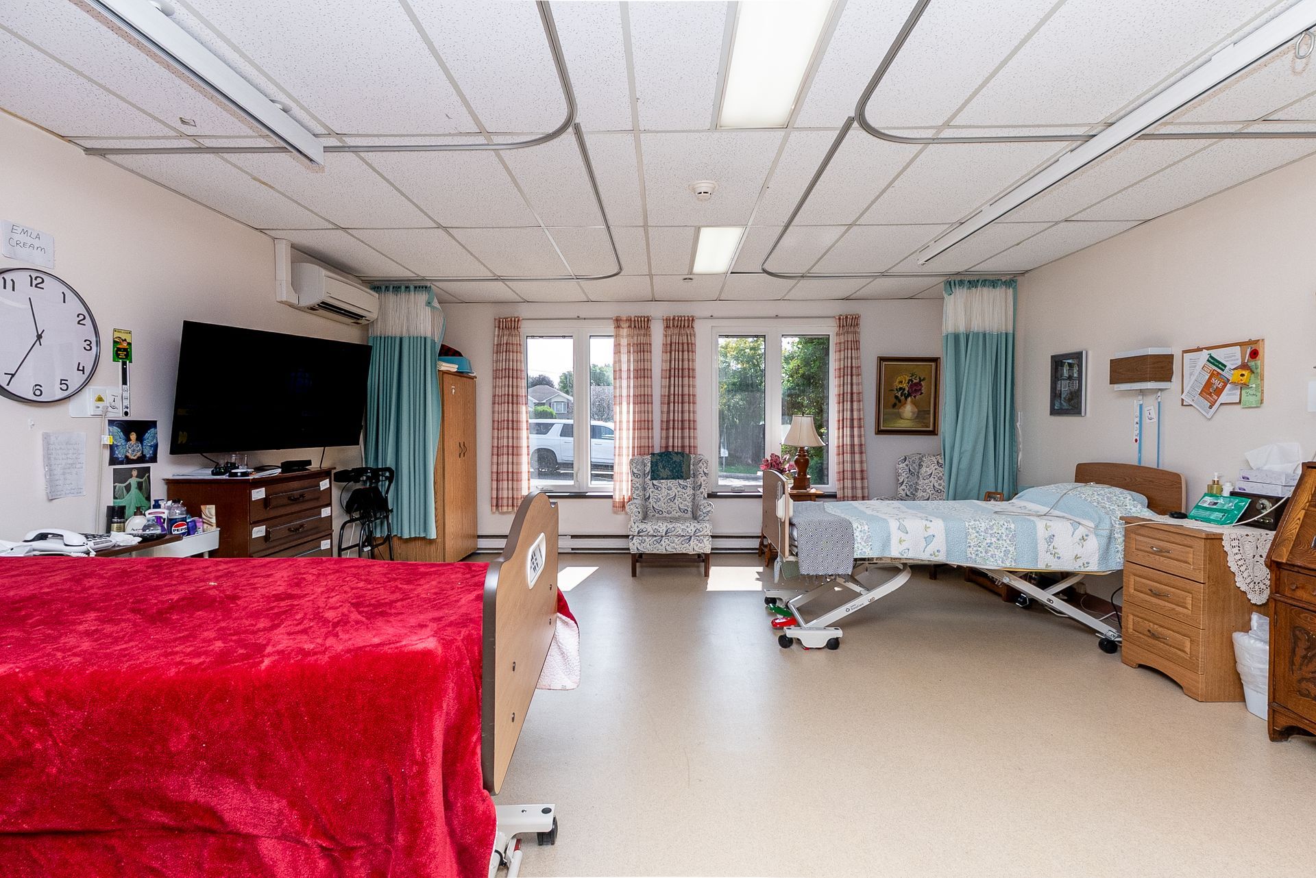 Hospital room with bed, TV, windows, and medical equipment, bright and tidy