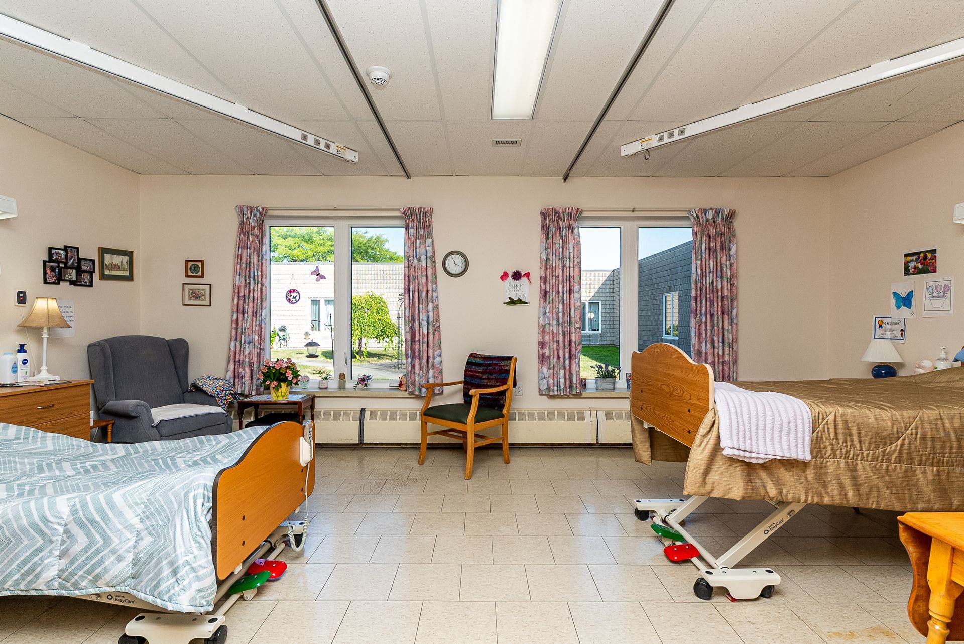 Spacious dorm room with two beds, desks, chairs, and a windowed door leading outside.