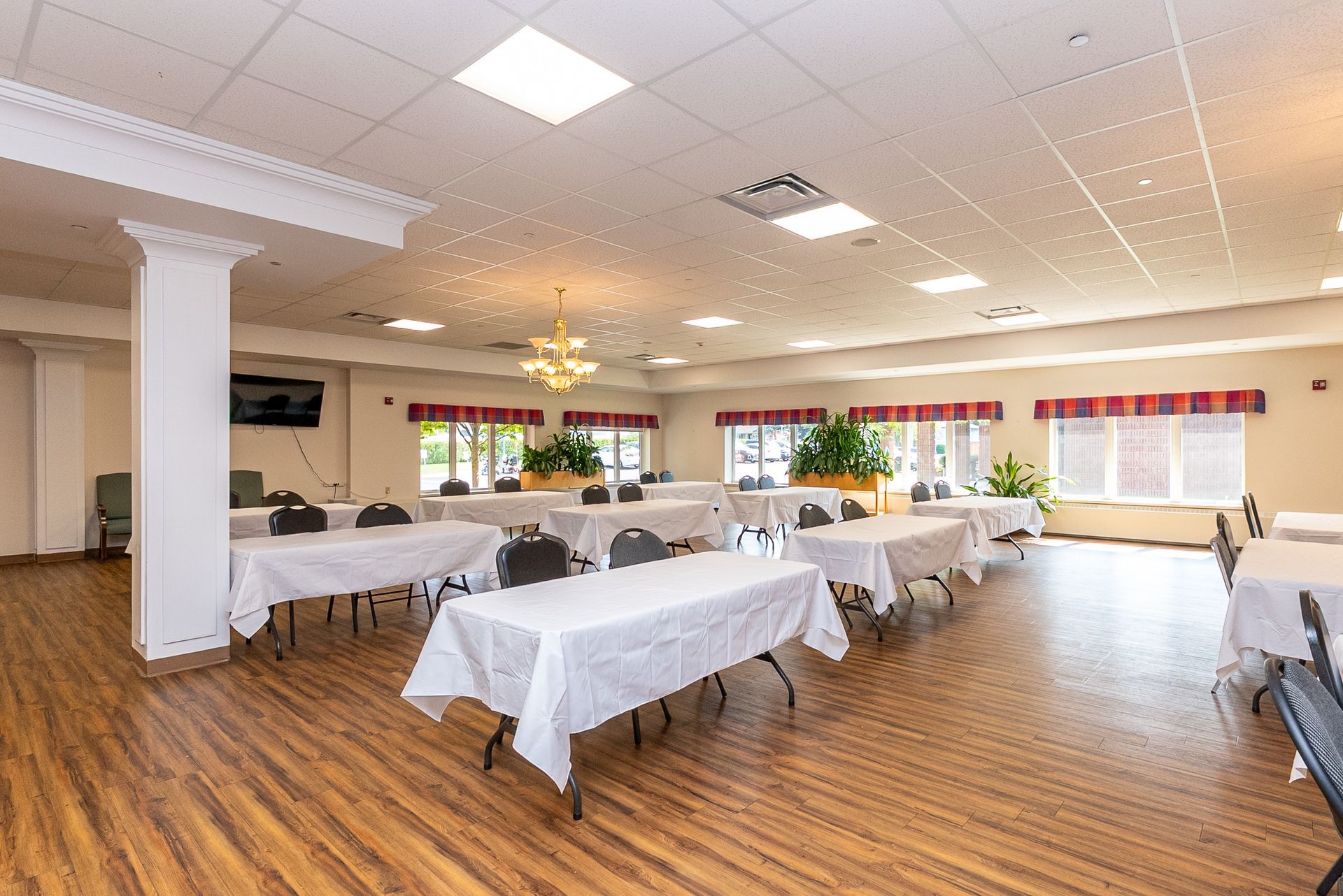 Bright banquet hall with white tablecloths, wood floors, and large windows.