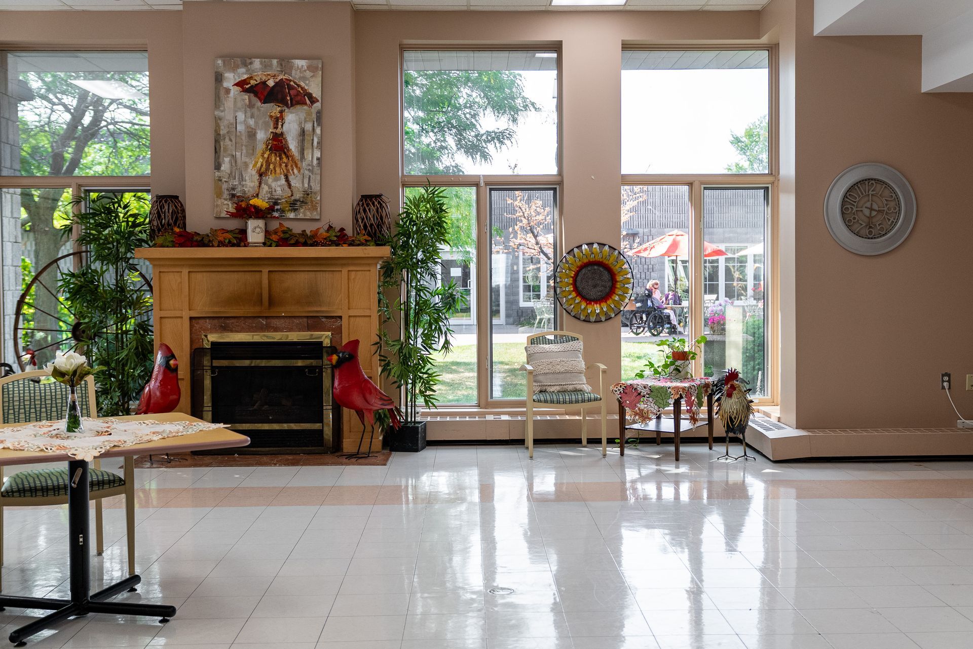 Bright lobby with a fireplace, large windows, reflective floor, and floral decor