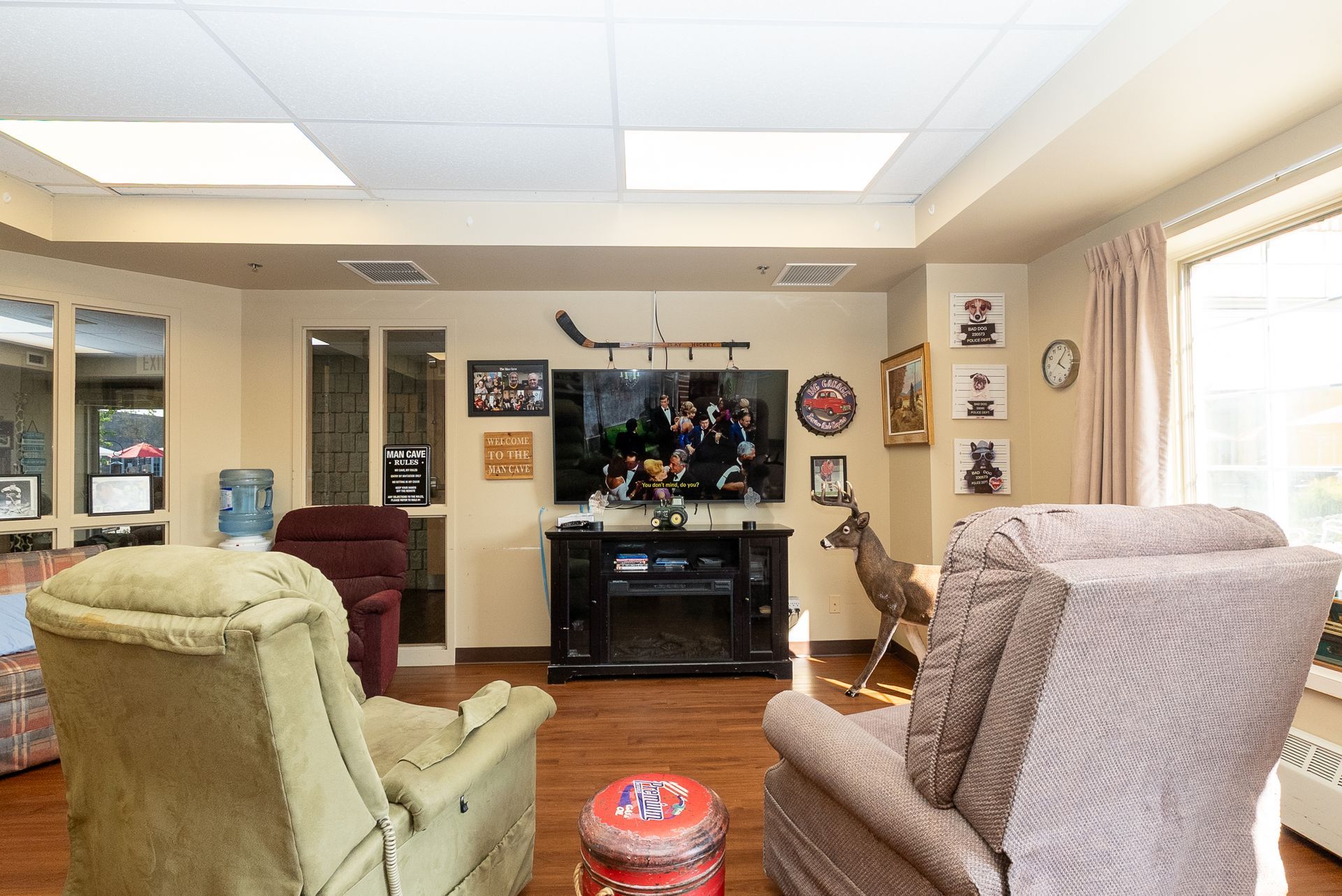 Living room with chairs, TV, and wall decor, with a deer statue near the center