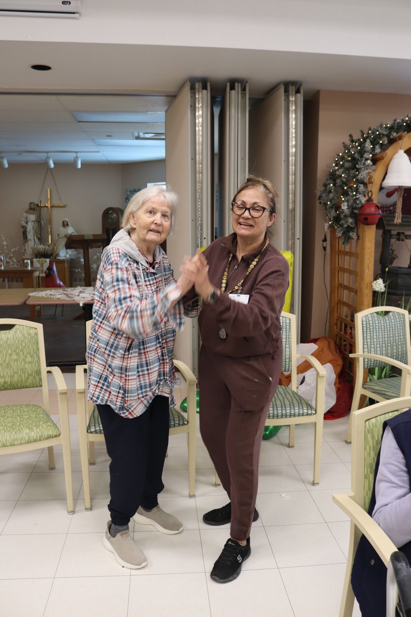 Two women dancing in a decorated indoor room, smiling and holding hands.