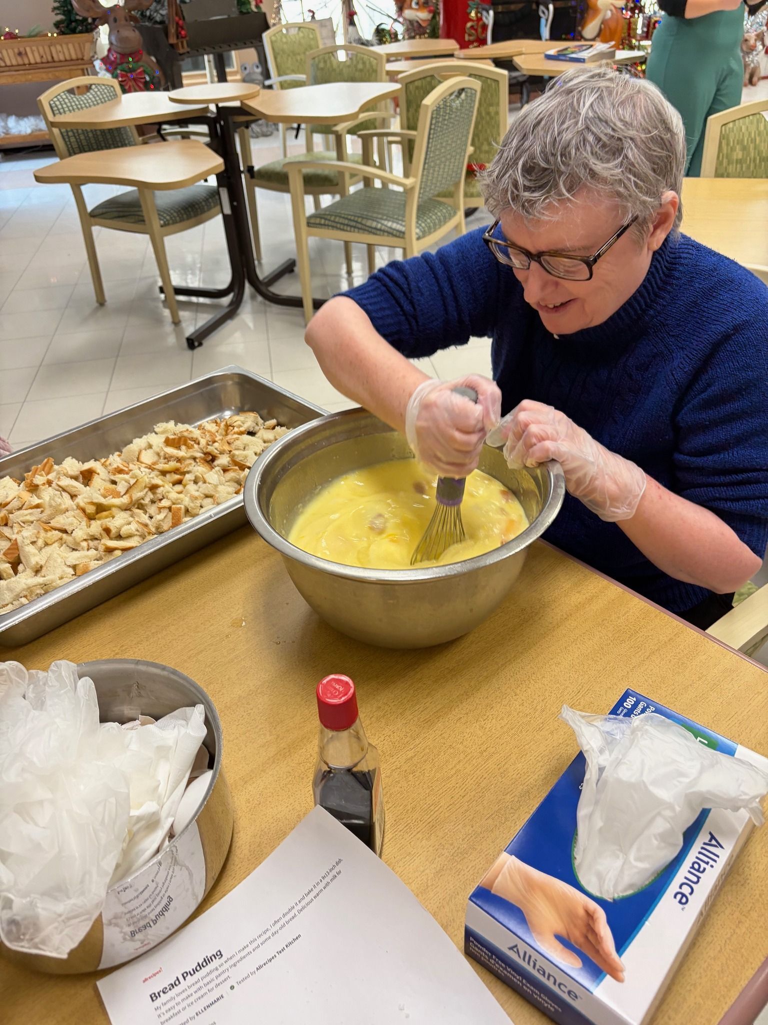 Person whisking batter in a large bowl at a table during a group cooking activity