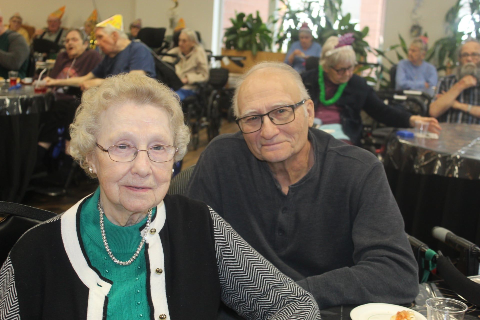 Two people seated at a banquet table, smiling in a crowded dining hall.