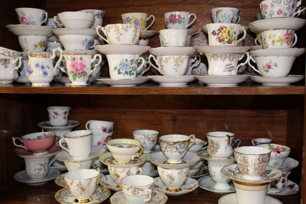 Shelves packed with assorted floral teacups and saucers in a cabinet