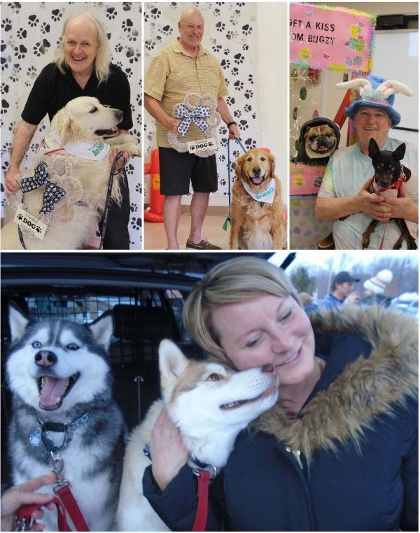 Woman with dogs at a pet event, smiling and cuddling a white dog in a winter coat