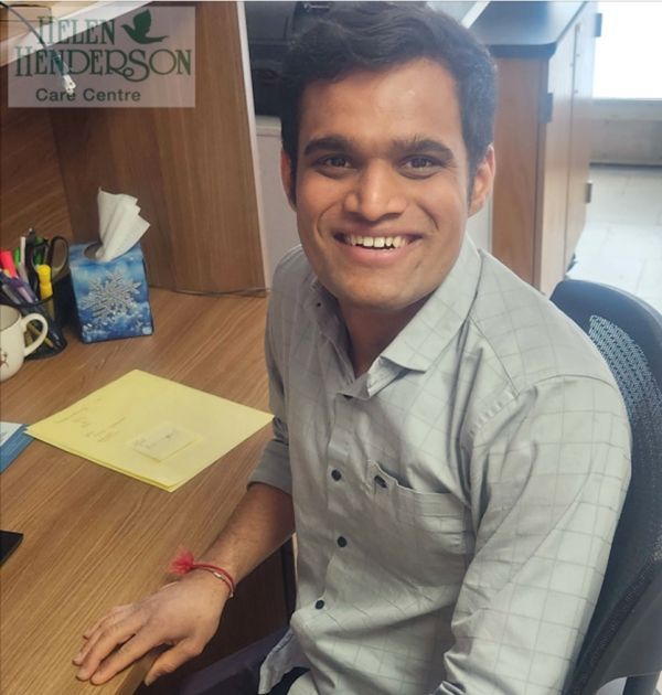 Smiling man seated at a desk in an office, looking at the camera.