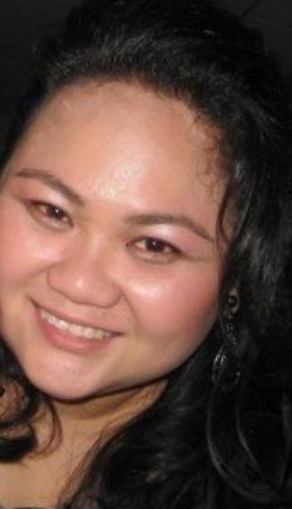 Smiling person with dark hair against a dark background