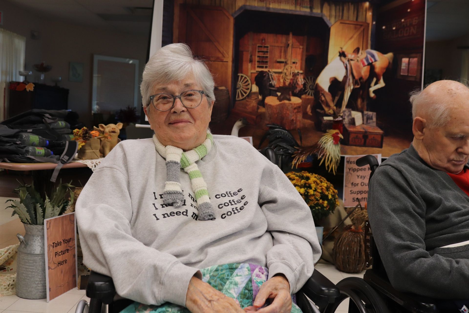 Two seated people in a cozy room, one smiling in a white sweatshirt, with a festive fireplace backdrop.