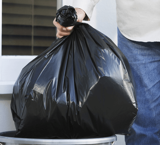 Closeup midsection of a man putting garbage bag into trash can