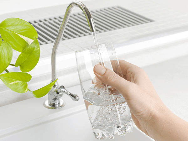 filling up a glass of water from the kitchen faucet