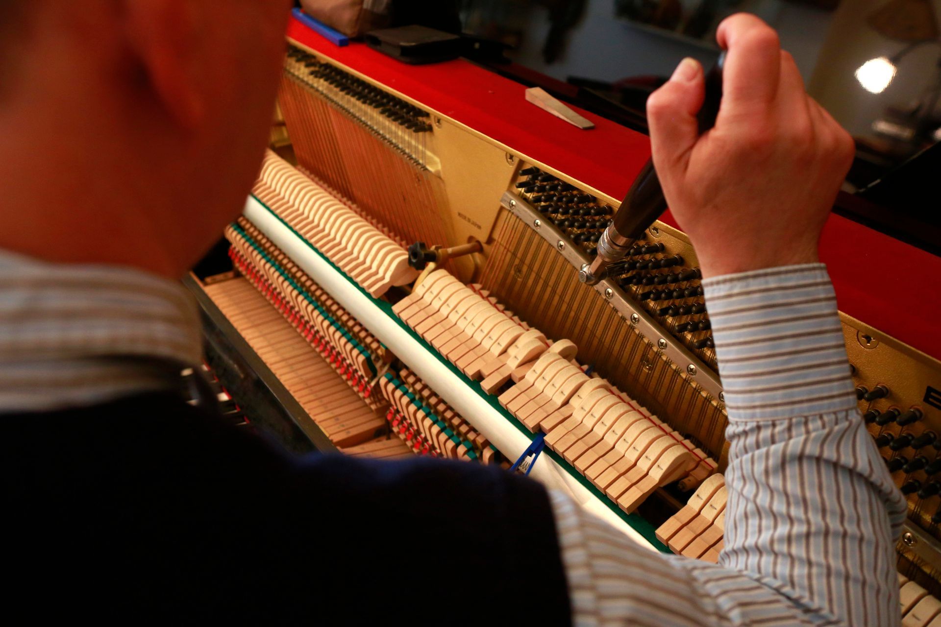 Close-up of a piano tuner at work, performing piano tuning services.