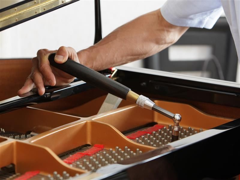 A piano tuner in Cumming, GA, from Atlanta Piano Tuner By Ear, adjusting grand piano strings using a