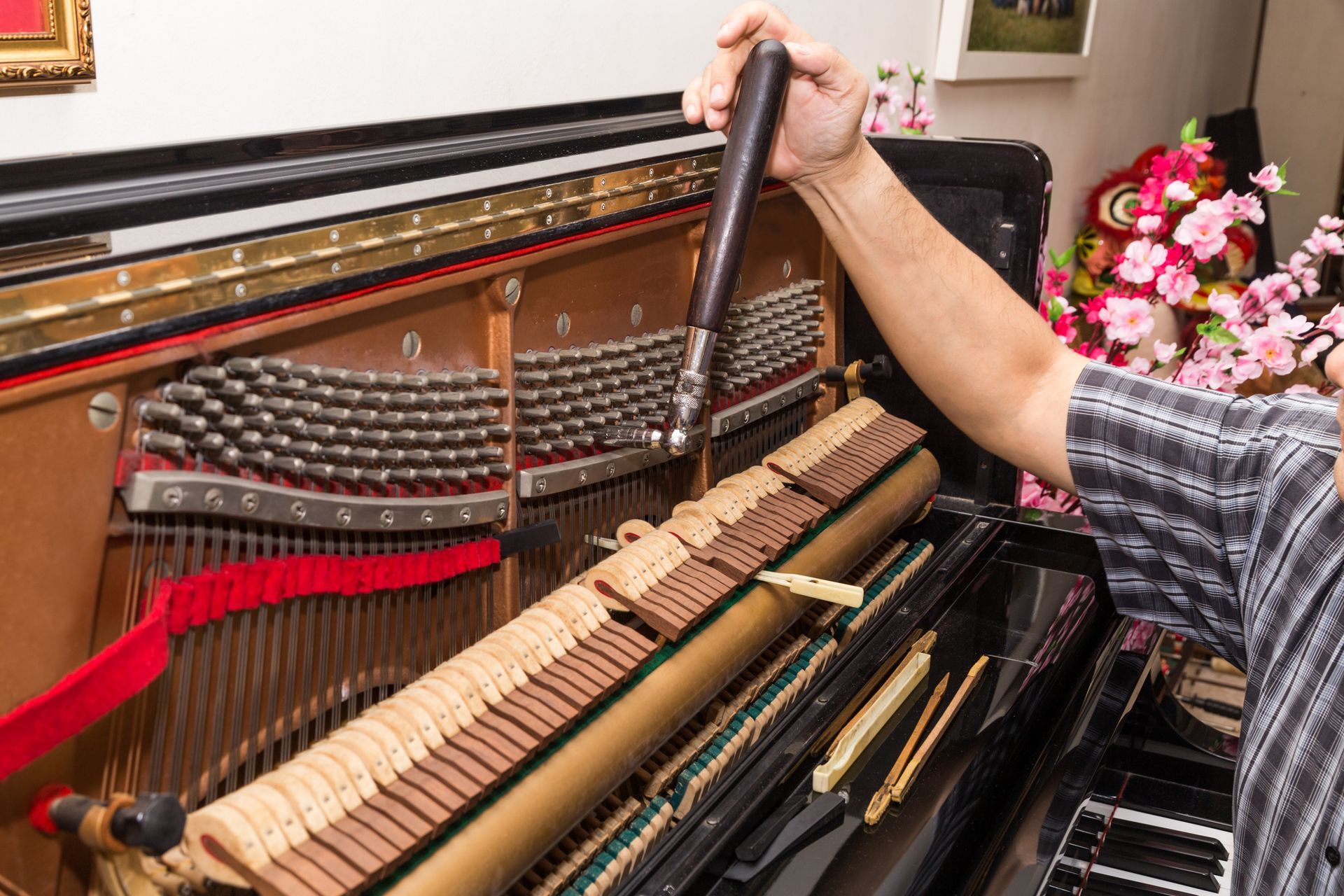 A technician repairing a grand piano in a studio, showcasing professional piano repair skills.