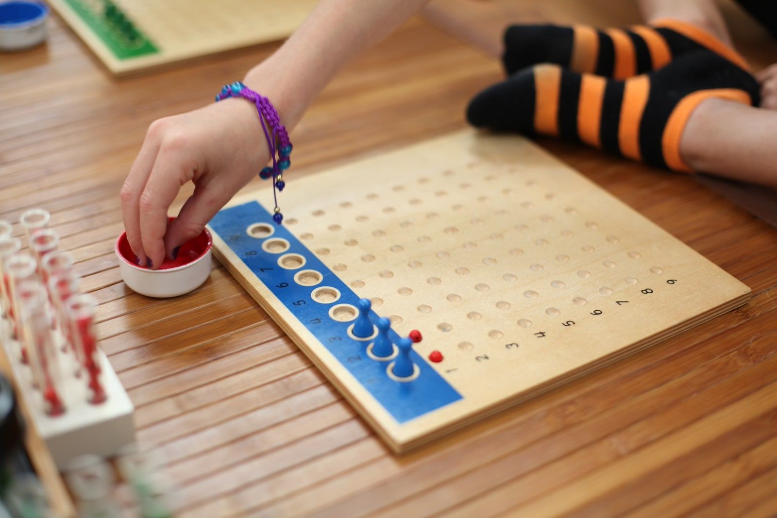 Child using Montessori bead board to learn multiplication and explore number patterns hands-on.