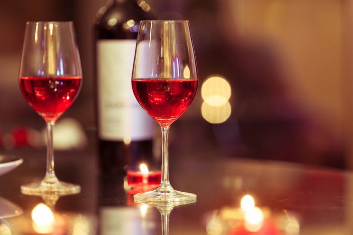 Pasta with tomato sauce, basil, and cheese on a white plate, with a fork and a glass.