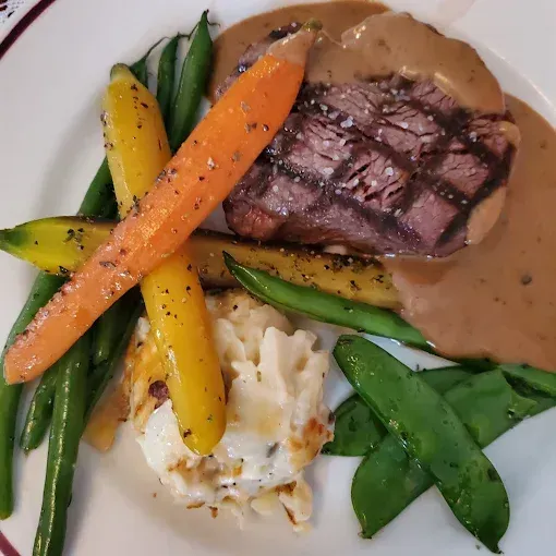 Table set with multiple plated dishes, wine glasses, and water carafe