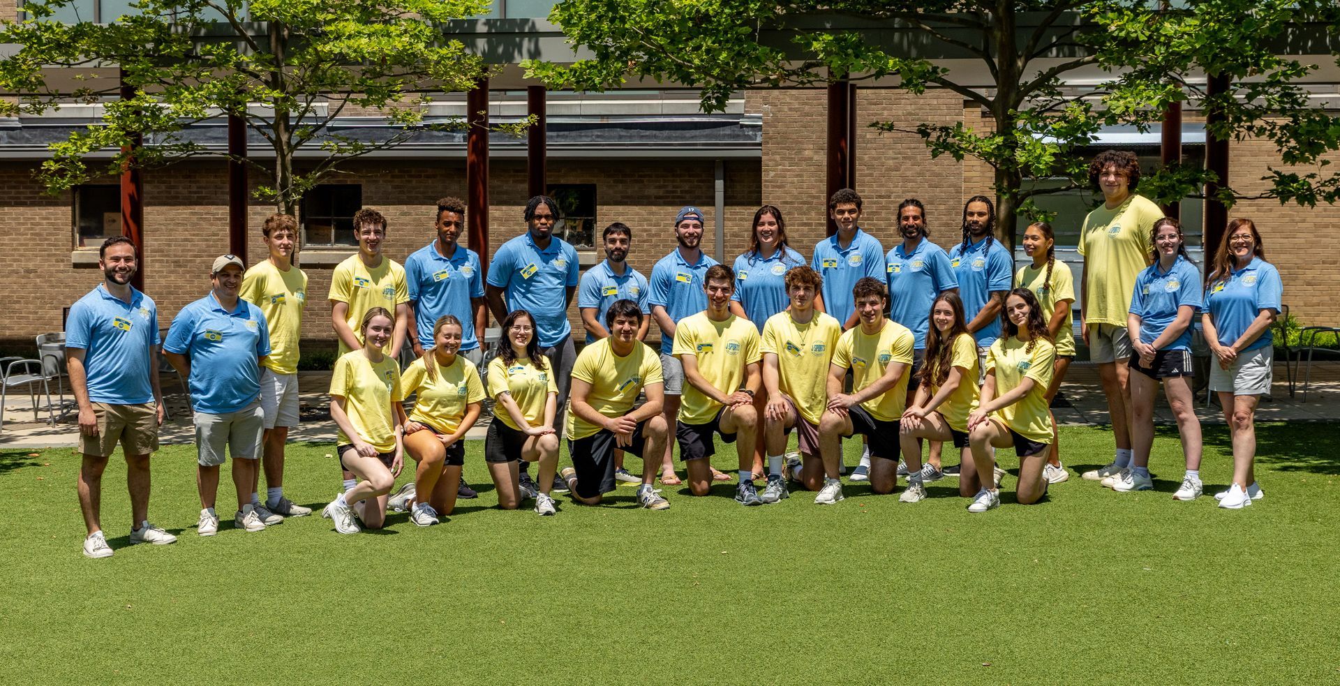 A group of counselors are posing for a picture on a lush green field.