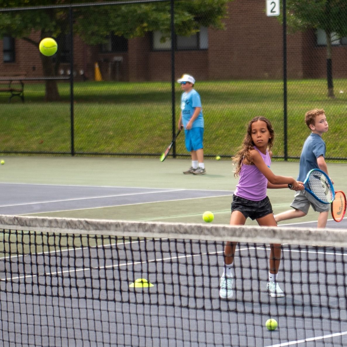 A boy and a girl are playing tennis on a court numbered 2