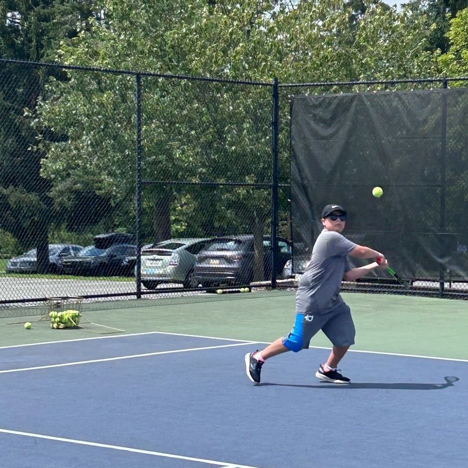 A man is swinging a tennis racket at a tennis ball on a tennis court.