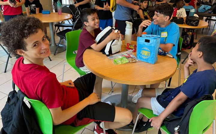 A group of young girls are sitting at tables in a cafeteria.