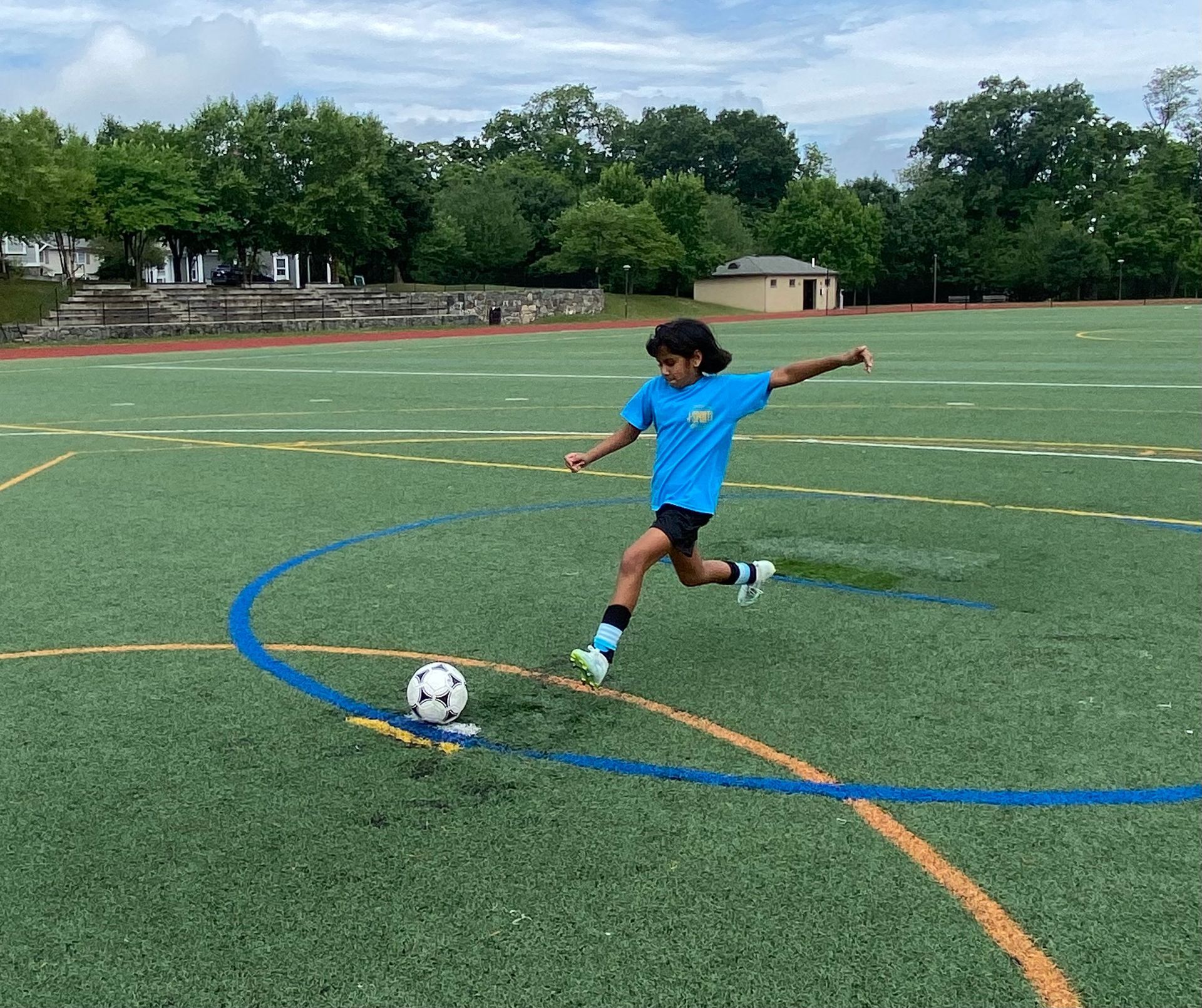 A young girl is kicking a soccer ball on a field.