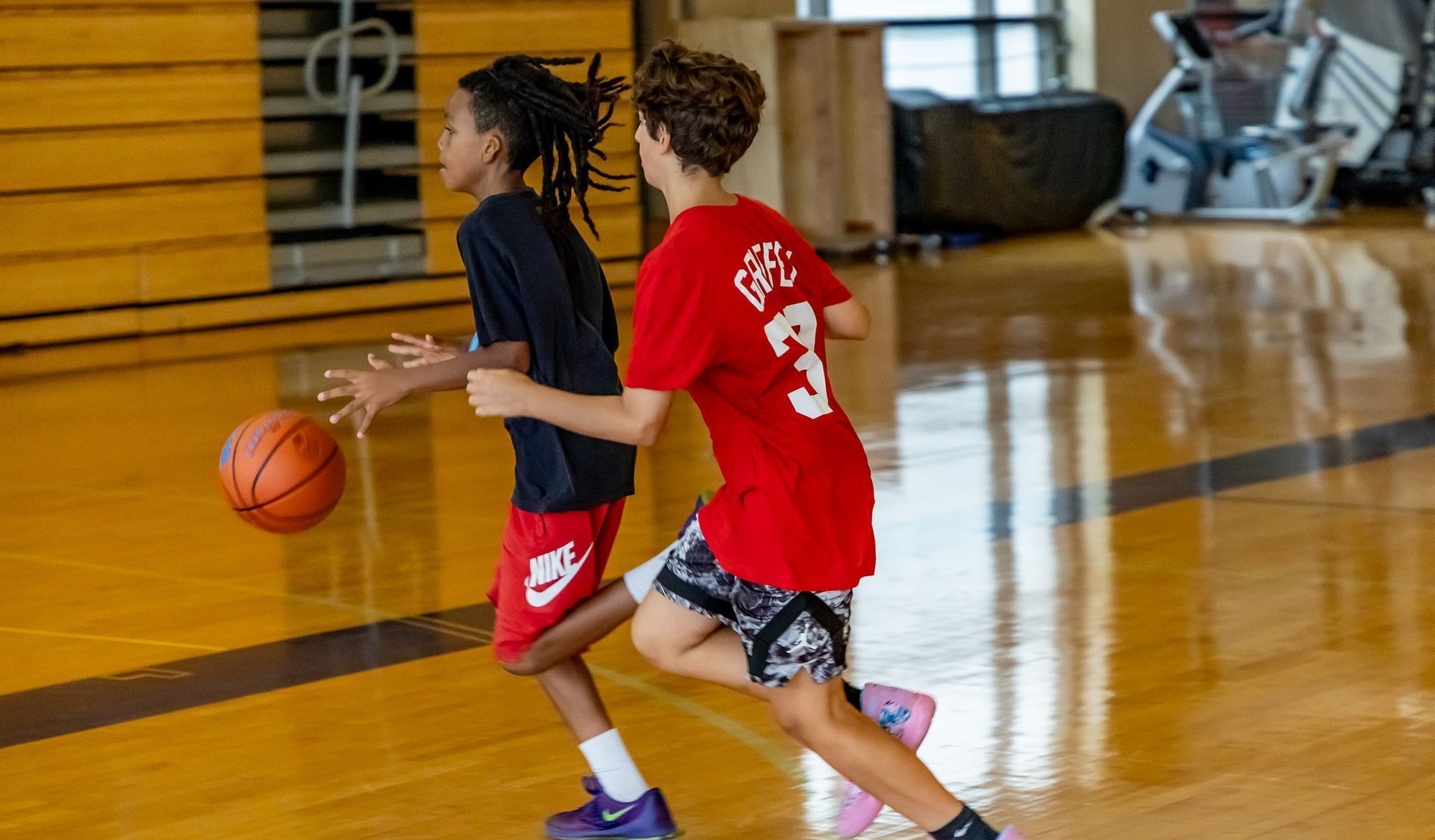 A group of children are playing basketball in a gym