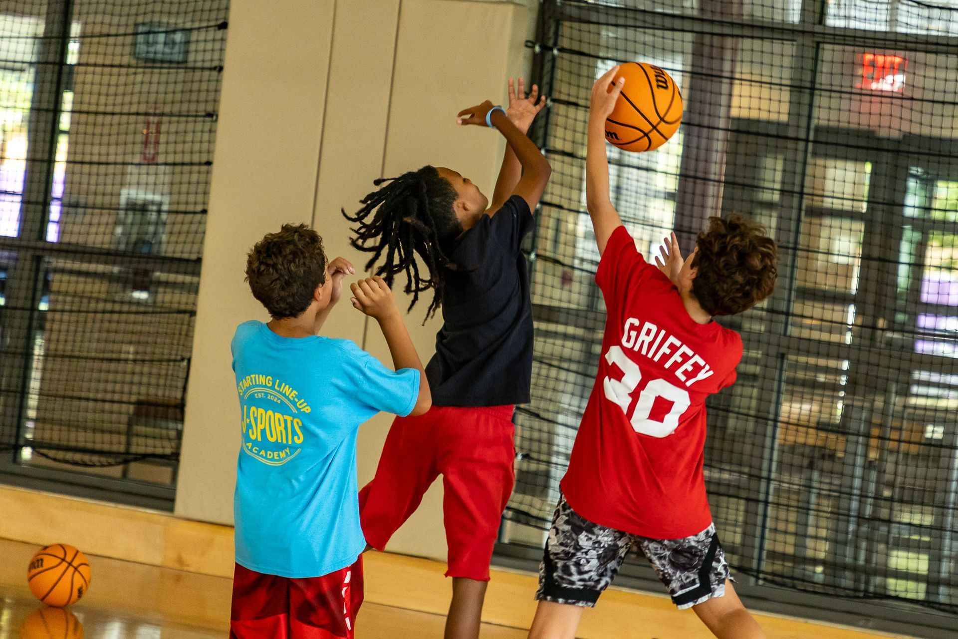A group of children are playing basketball in a gym