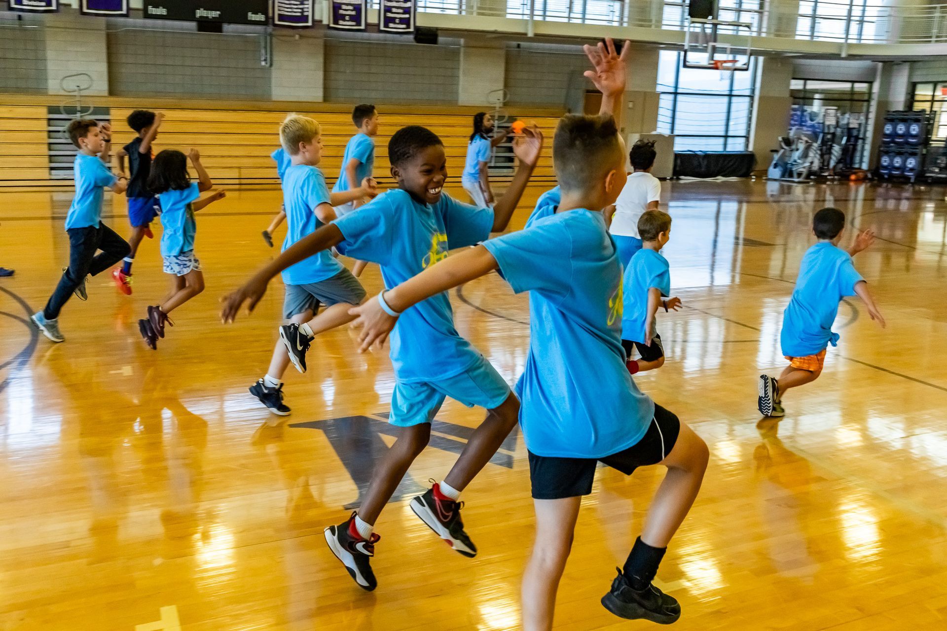 Children in blue shirts exercising in a gymnasium.