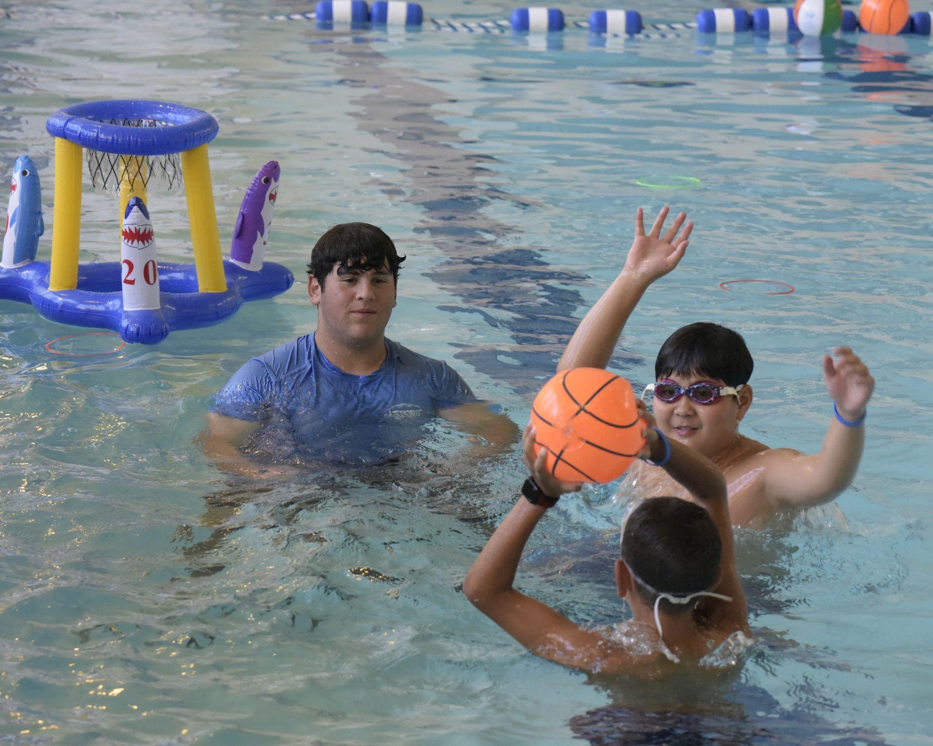 A group of children are playing with a basketball in a swimming pool