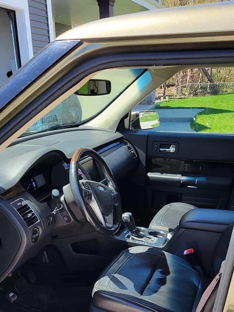 Interior view of a beige Ford Flex, showcasing the dashboard, steering wheel, and front seat. | Joe's Slinger Service
