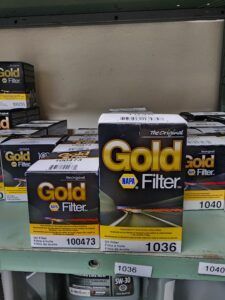 Several NAPA Gold oil filter boxes on a shelf. The boxes are black and yellow with white text. | Joe's Slinger Service