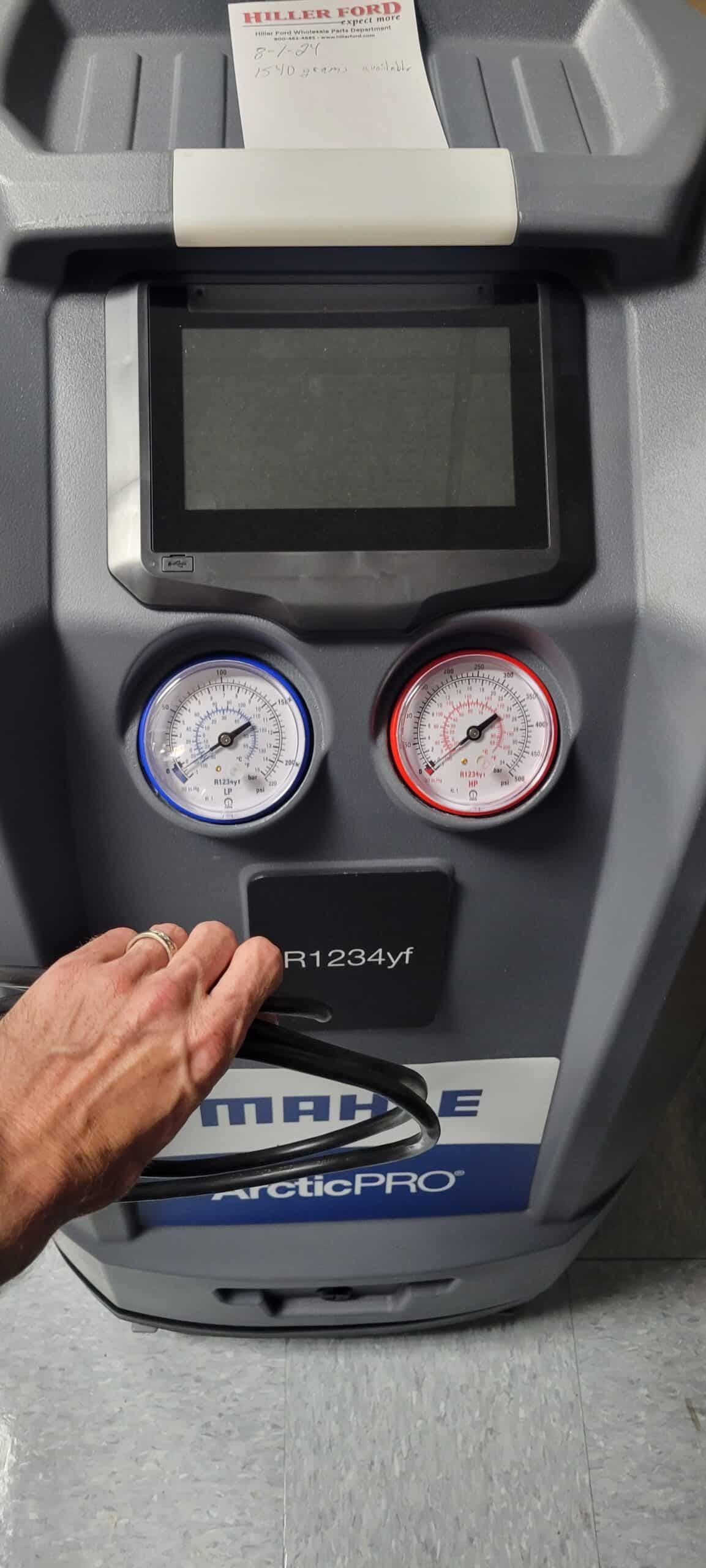 Gray and blue automotive air conditioning machine with gauges and screen, hand holding handle. | Joe's Slinger Service