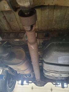 Underside of a vehicle showing a rusted driveshaft, exhaust, and fuel tank. | Joe's Slinger Service