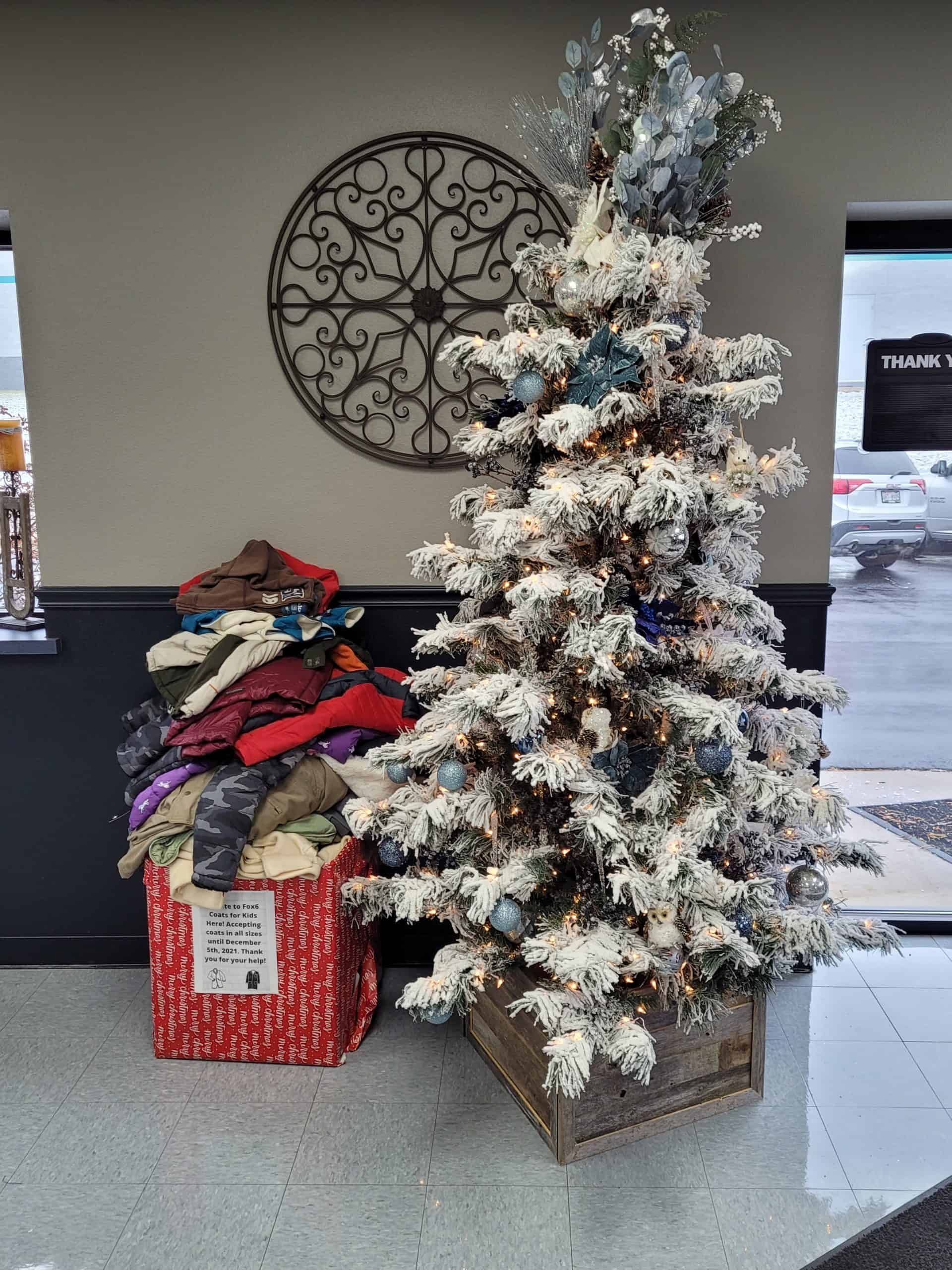 Flocked Christmas tree and donation box filled with clothing, inside a building. | Joe's Slinger Service