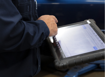 Mechanic in blue jumpsuit using a tablet to diagnose a vehicle. | Joe's Slinger Service