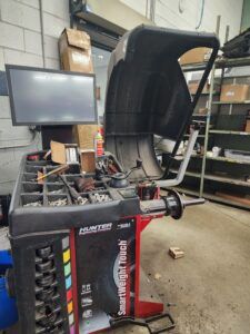 Hunter tire balancing machine in a garage. Black, red, and silver. A computer monitor is visible. | Joe's Slinger Service