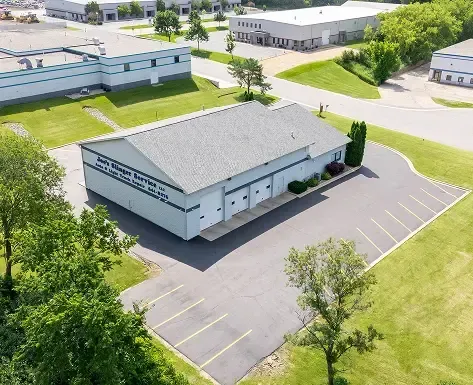 Aerial view of a commercial building with a gray roof and parking spaces.