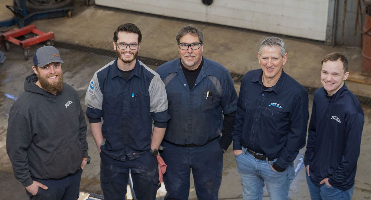 Woman and man at desk, discussing documents. Man points at files, woman looks on. Office setting. | Joe's Slinger Service