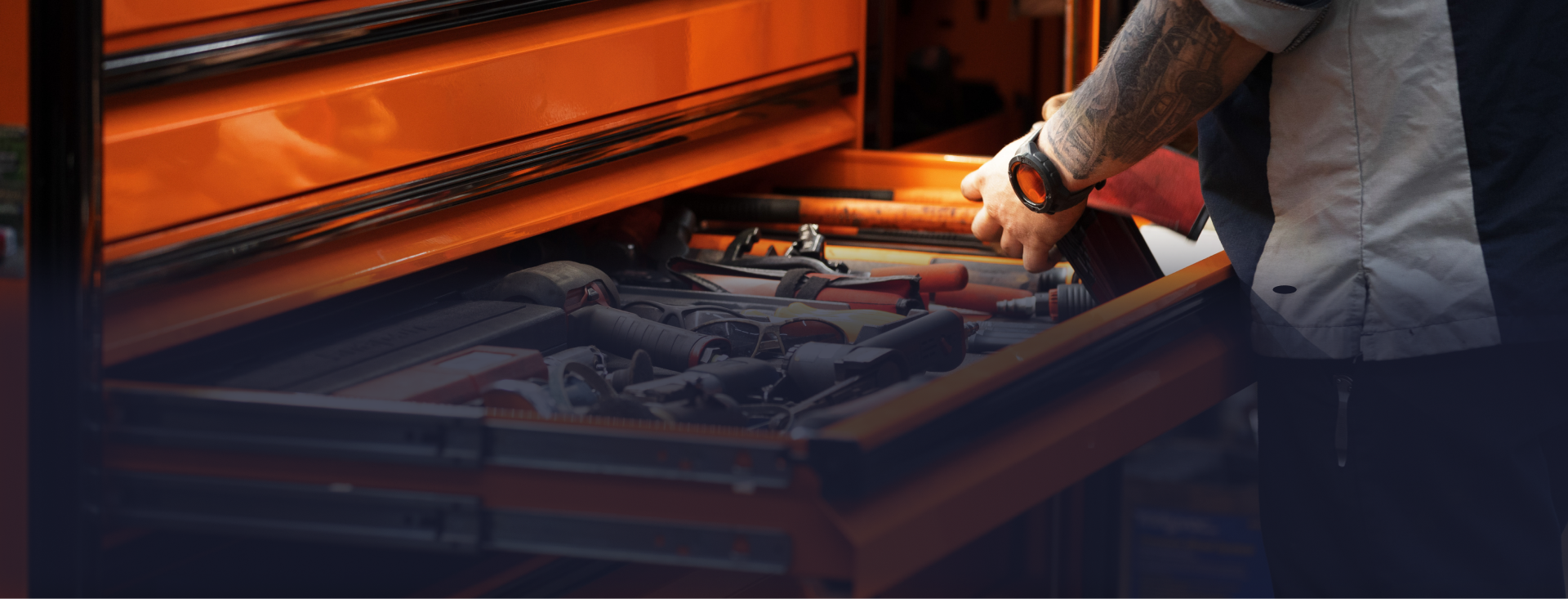 Person reaching into an orange toolbox filled with tools, possibly in a garage. | Joe's Slinger Service